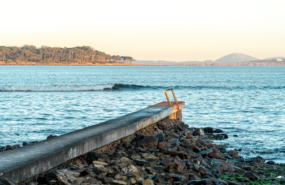 una panchina di legno seduta sulla cima di una spiaggia rocciosa