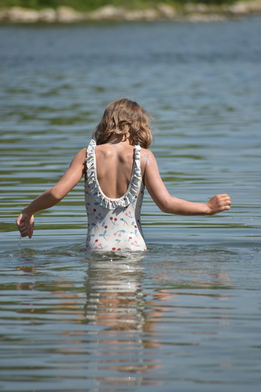 a girl in a body of water with her arms outstretched