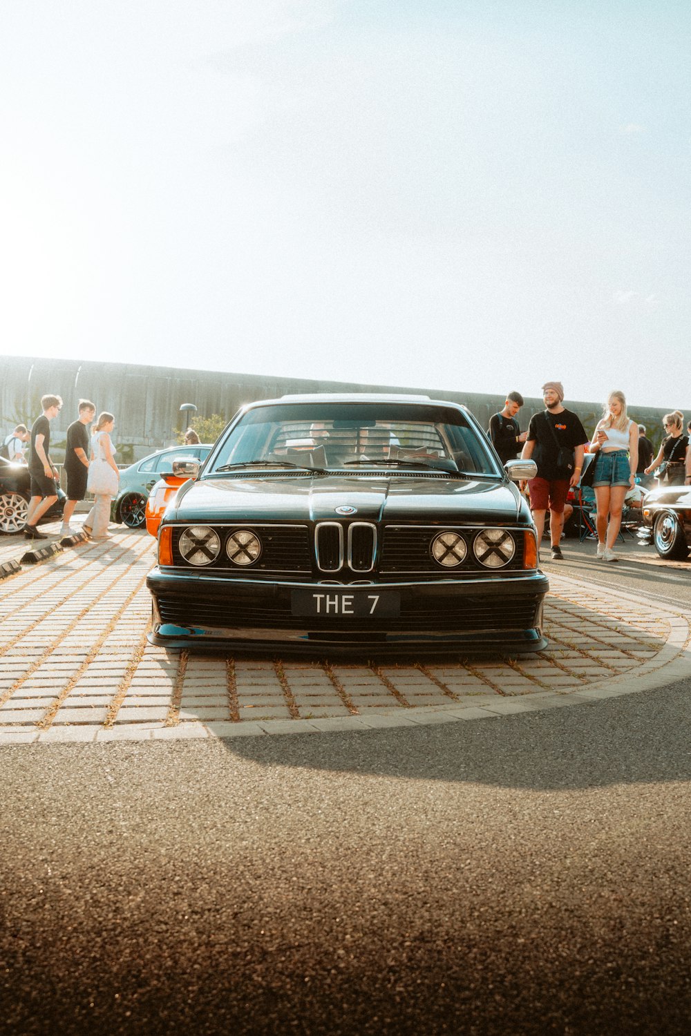 a black car parked in front of a group of people