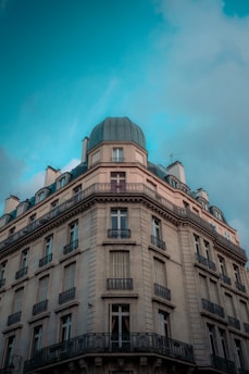 A classic French-style apartment building with ornate balconies and a rounded, domed roof. The architecture features multiple stories with tall windows and intricate detailing.
