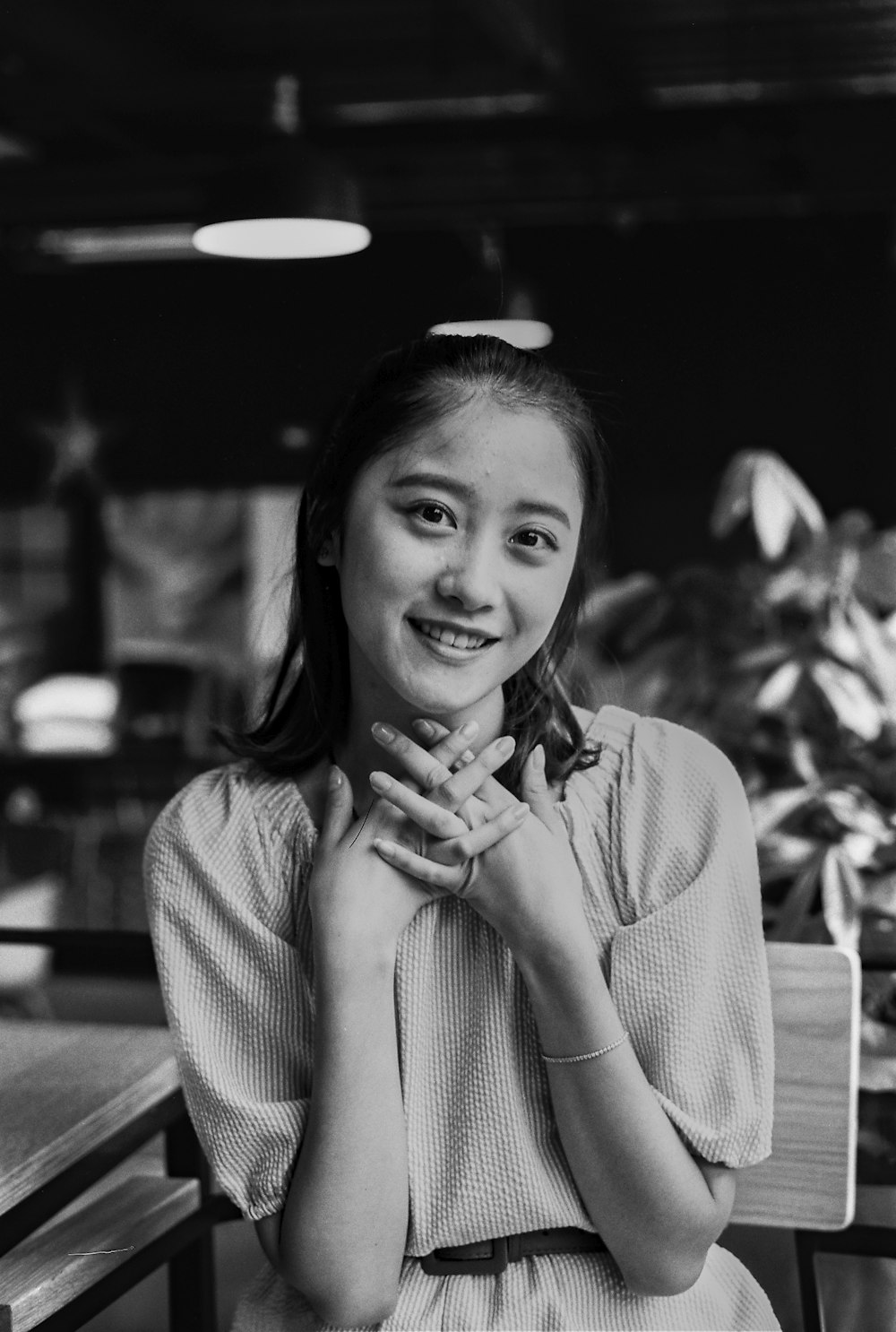 a woman sitting at a table with her hands together