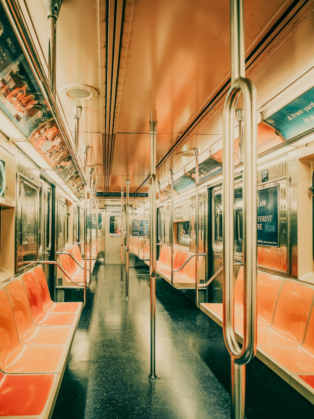 an empty subway car with orange seats and railings