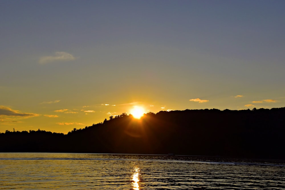 Il sole sta tramontando su un lago con una barca nell'acqua