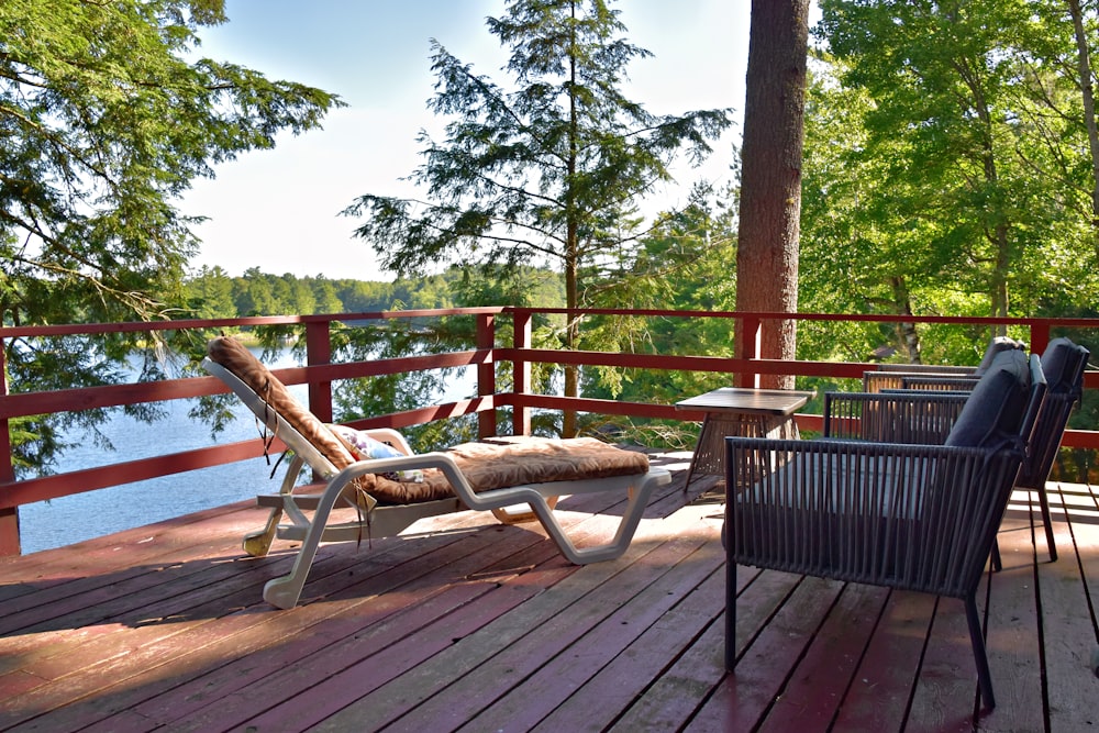 a chair and a table on a deck overlooking a lake