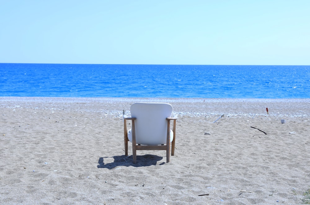 a white chair sitting on top of a sandy beach