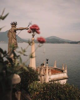 a statue of a man holding a flower next to a body of water