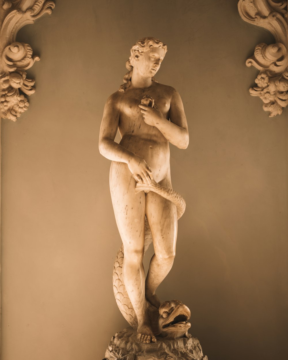 a statue of a naked man holding a snake