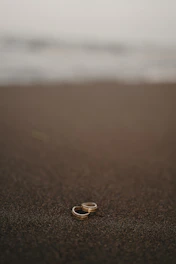 Bright and stylish rings stacked on a sandy beach background at sunset.