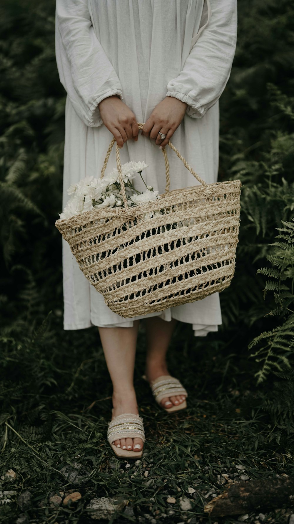 a woman in a white dress holding a wicker basket