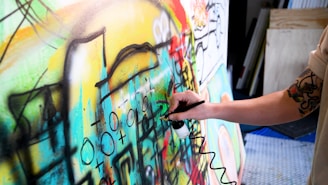 a person painting a wall with colorful graffiti