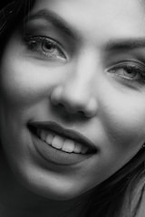 An intimate close-up of a female star’s confident smile, set against a sleek black background.