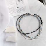 A collection of copper necklaces laid out on natural linen fabric with soft shadows.