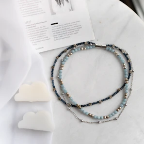 A collection of lace necklaces arranged on a vintage wooden table with golden accents and soft cream linens