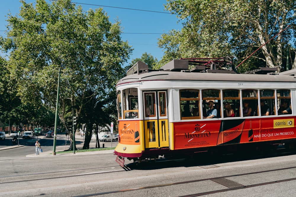 a red and yellow trolley car traveling down a street