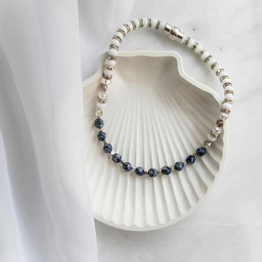 a white shell with a blue beaded necklace on it