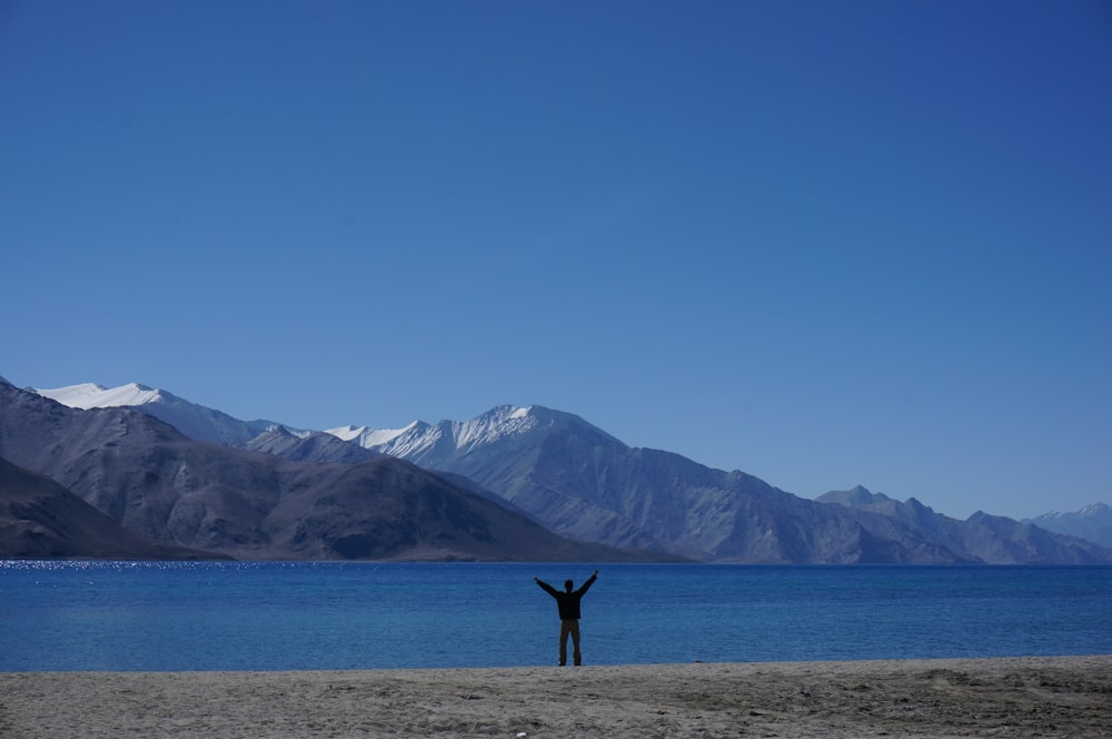 a person standing on a beach with their arms in the air