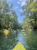 Wide shot of a float trip group drifting down the San Juan River under a bright blue sky