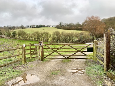 A sturdy wooden gate fitted at the entrance of a rural farm property.