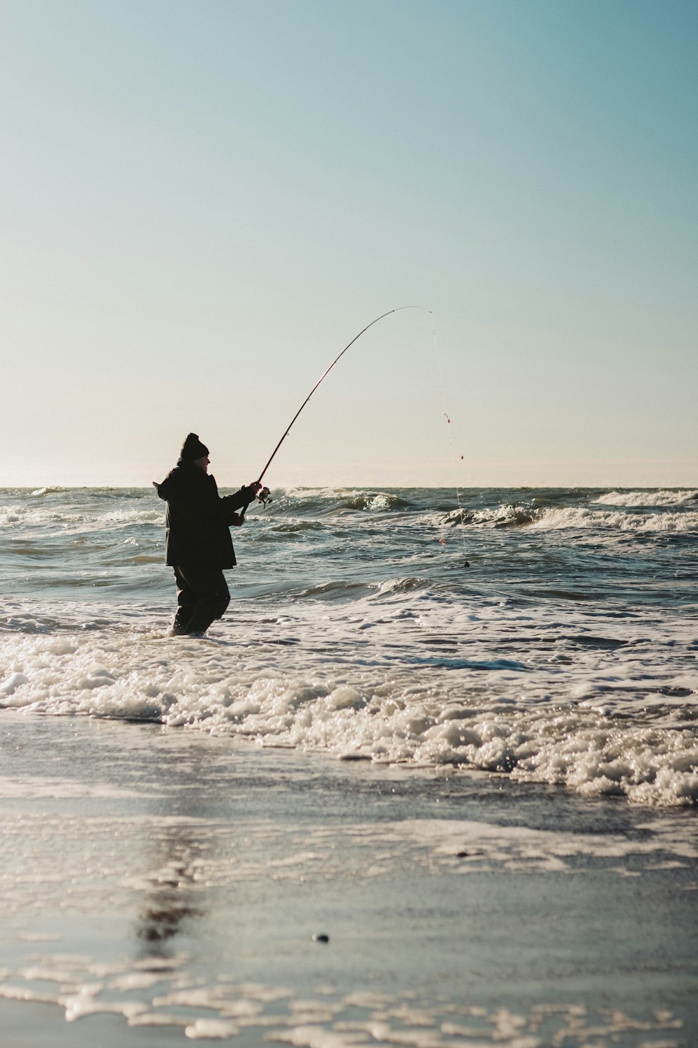 a person standing in the water with a fishing rod