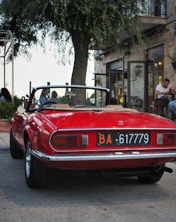 A classic vintage convertible parked in front of a charming city café on a sunny day.