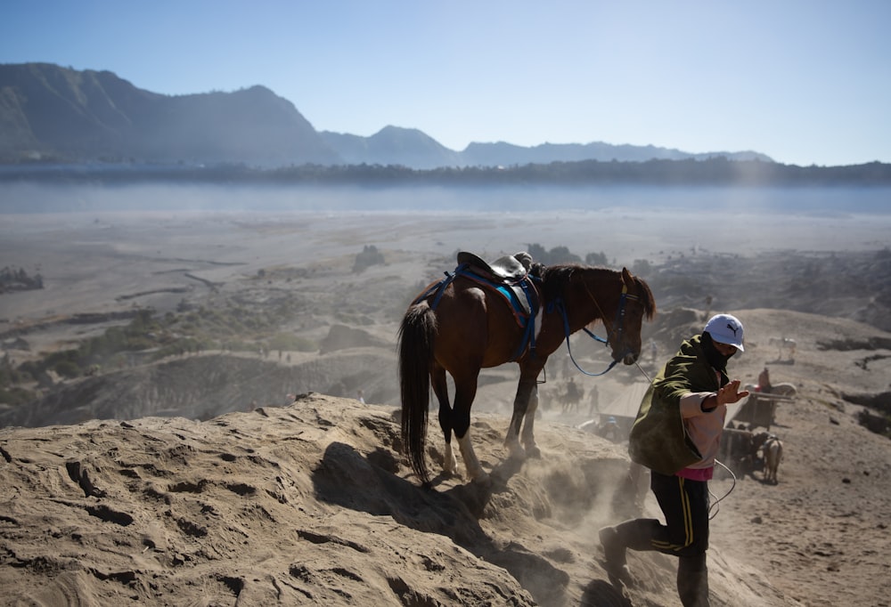 a man is leading a horse up a hill