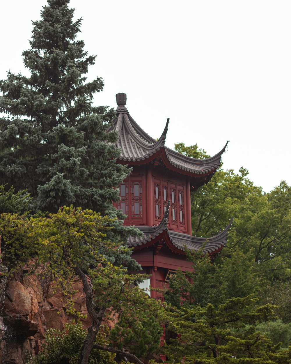 a tall red building sitting on top of a lush green forest