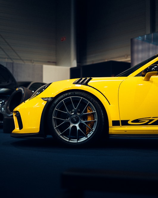 A sleek yellow car with spinning wheels on a dark gray background.