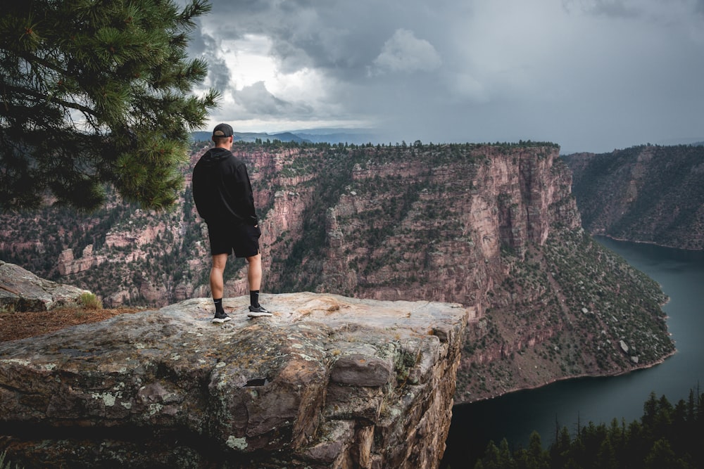 a man standing on top of a cliff overlooking a lake