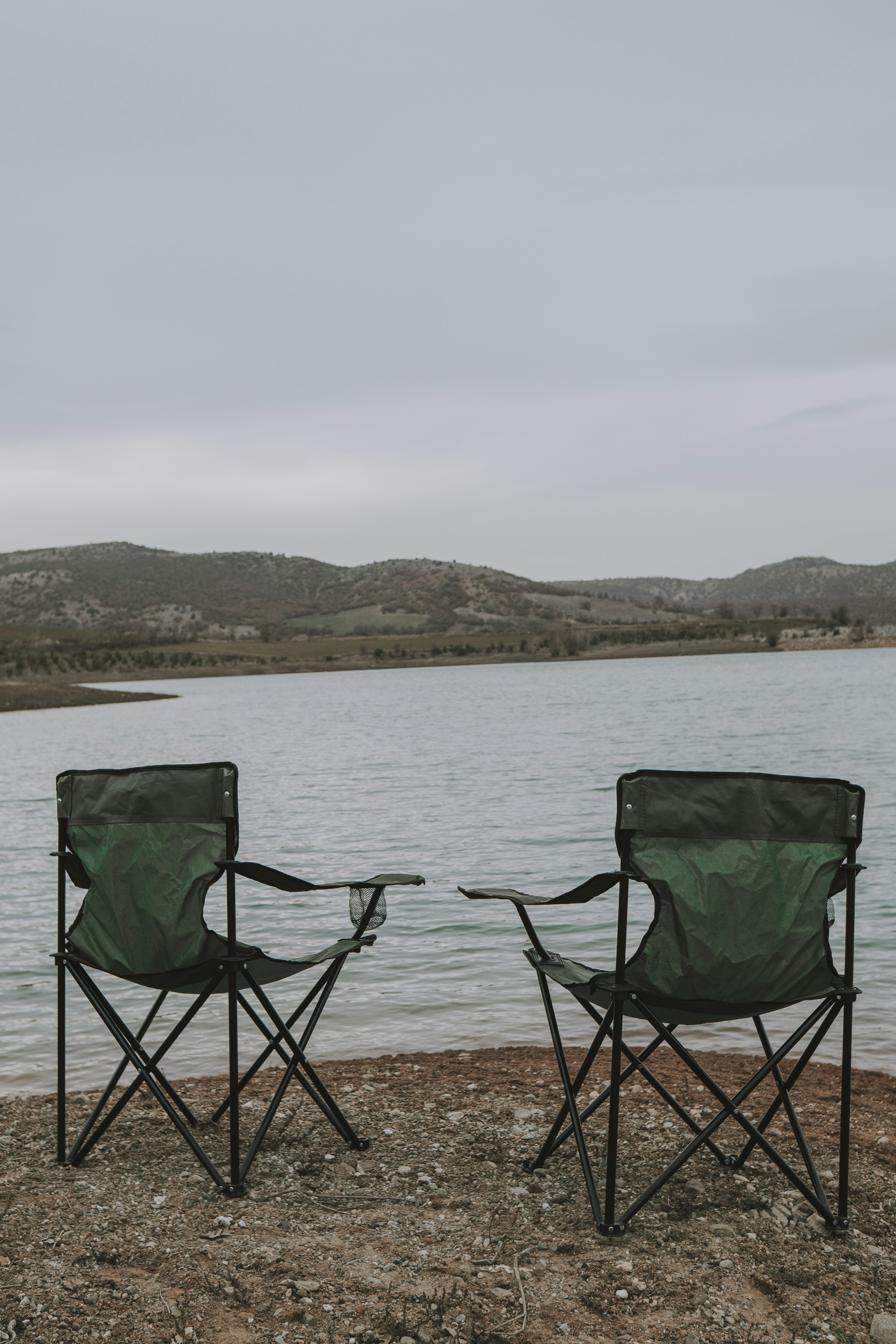 a couple of chairs sitting next to a body of water