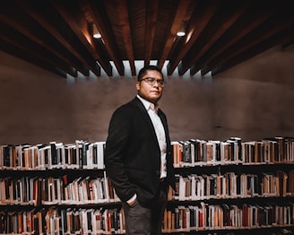 a man standing in front of a book shelf filled with books