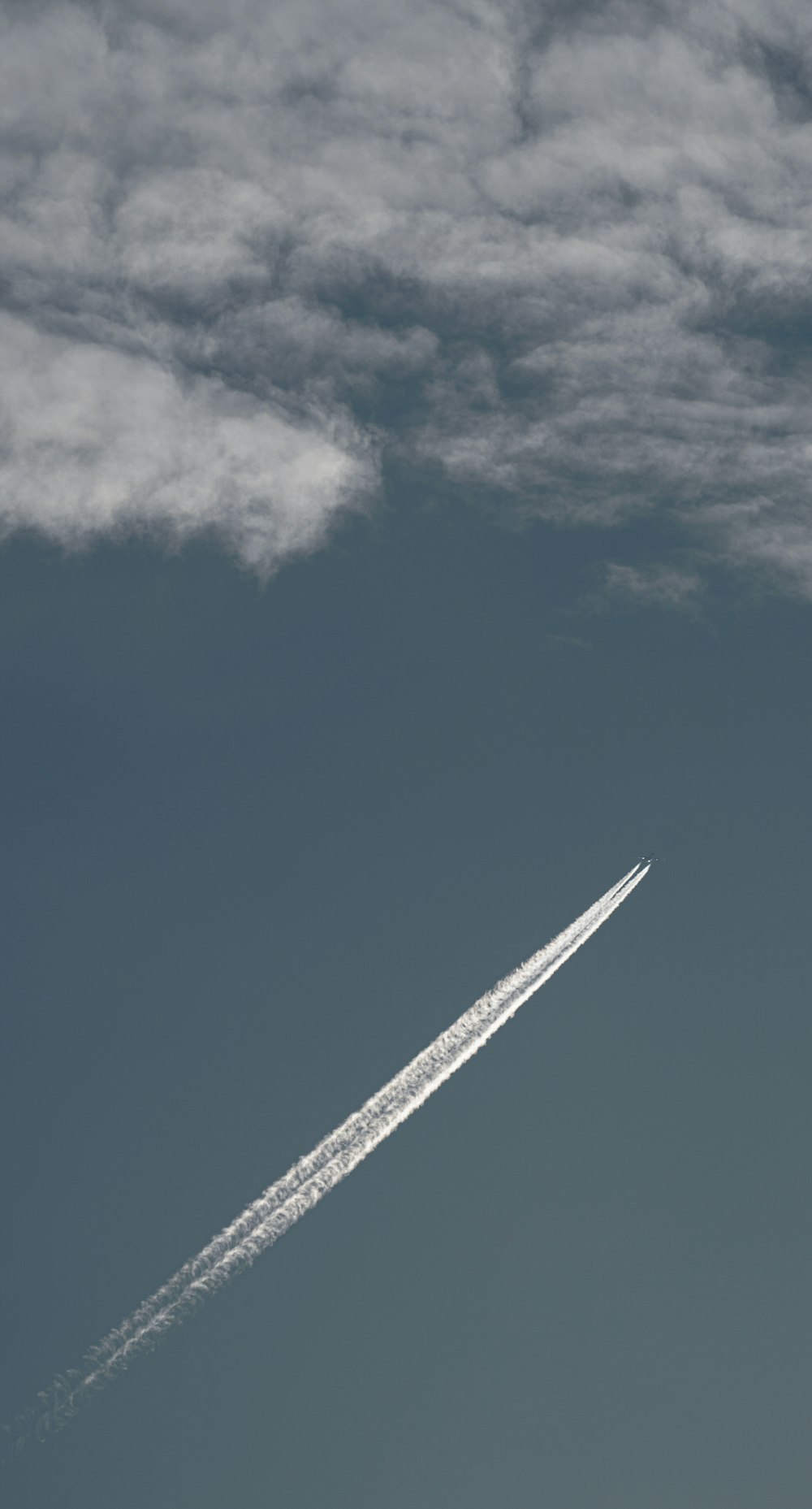 a jet flying through a cloudy blue sky