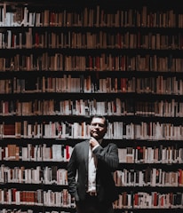 Portrait of Lic. David Angulo de Haro in a thoughtful pose, surrounded by books.