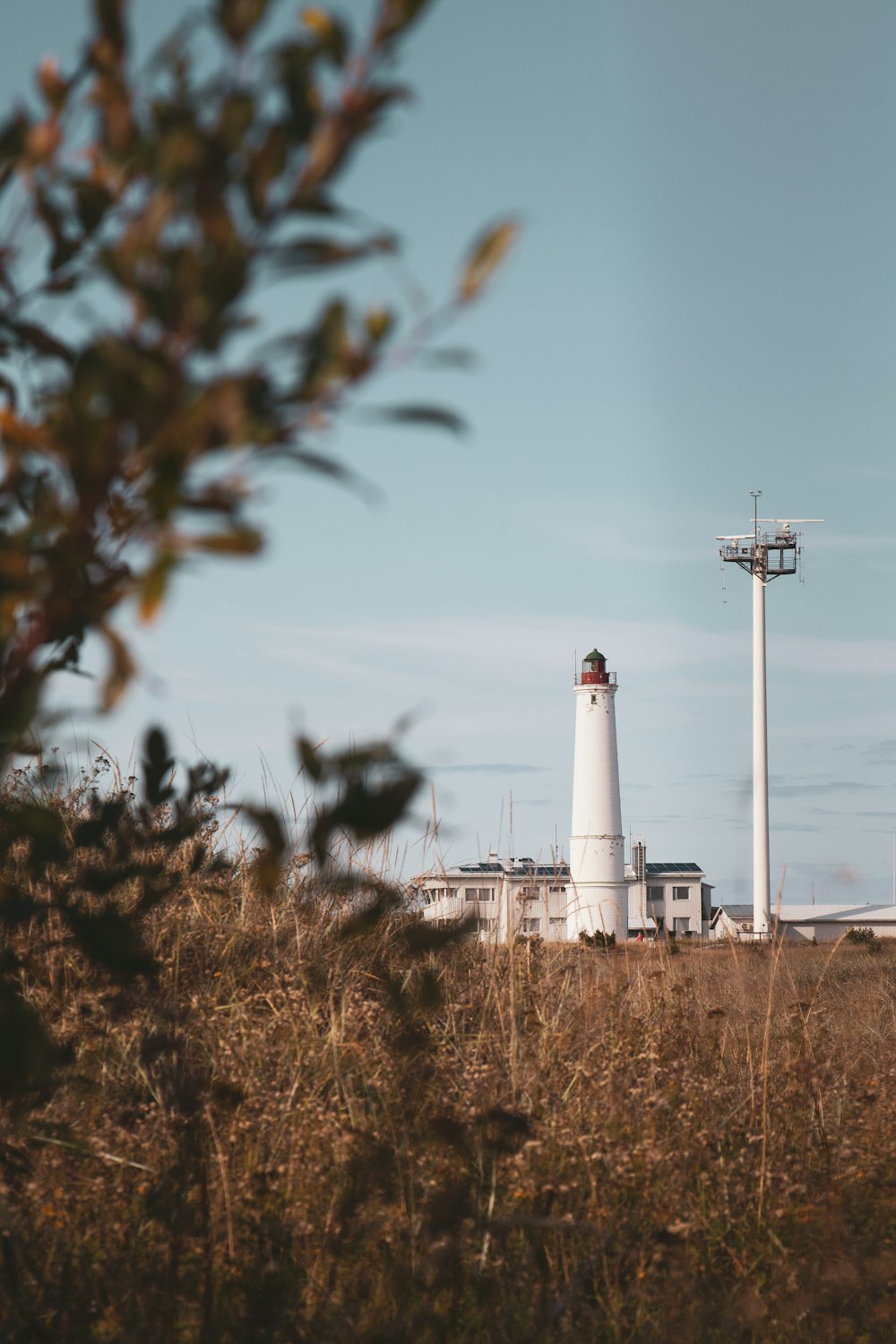 a tall white light house sitting in the middle of a field