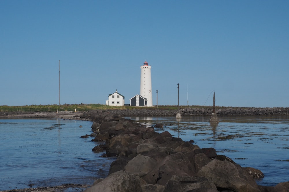 un phare assis au sommet d’une colline à côté d’un plan d’eau