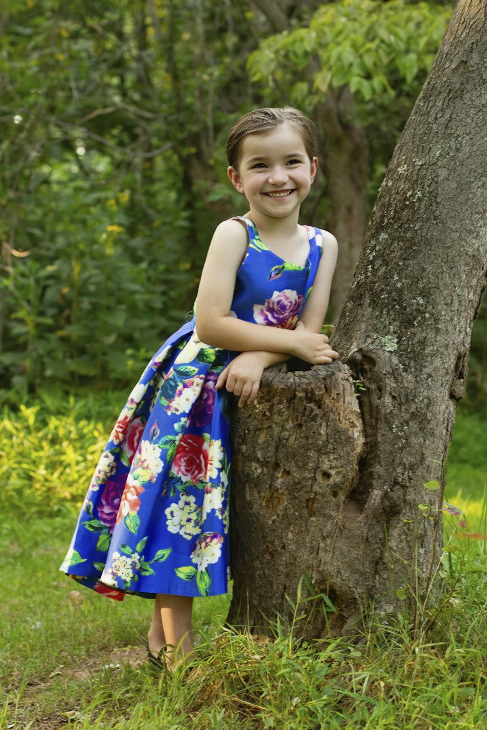 a little girl standing next to a tree