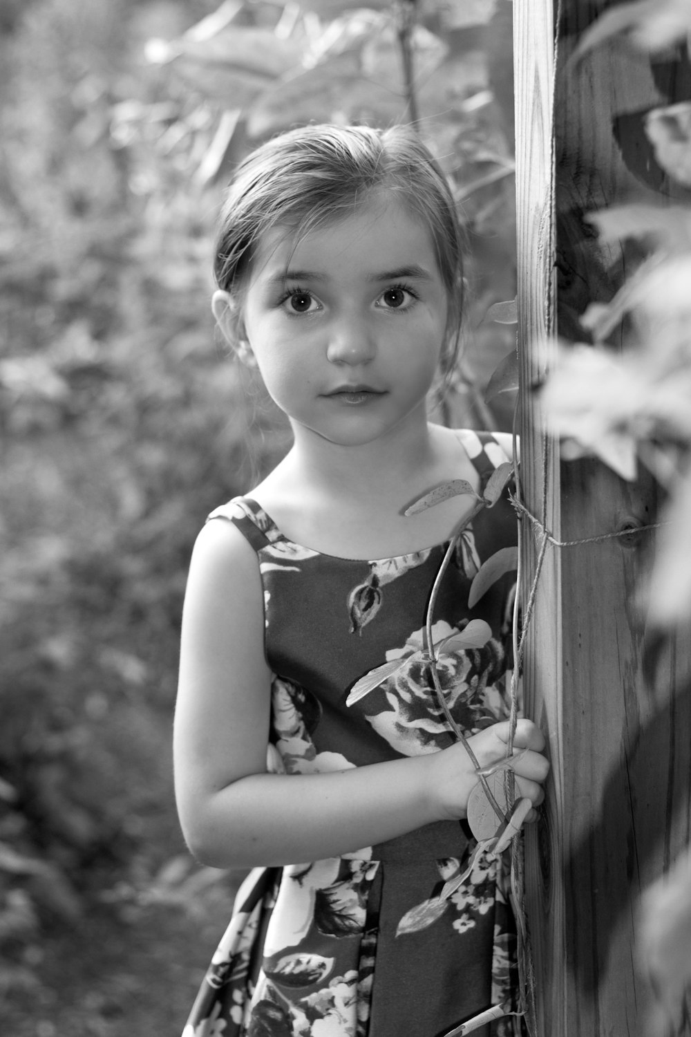 a little girl standing next to a wooden fence