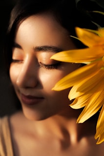 Close-up of a serene woman practicing mindfulness in a sunlit room with green plants.