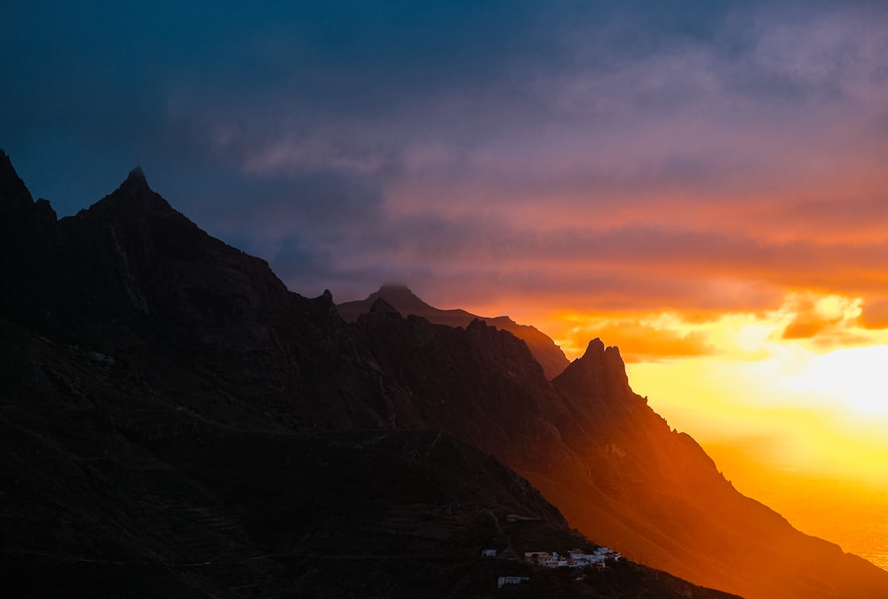 the sun is setting over a mountain range