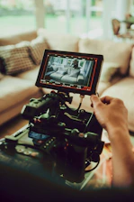 a person holding a video camera in front of a couch