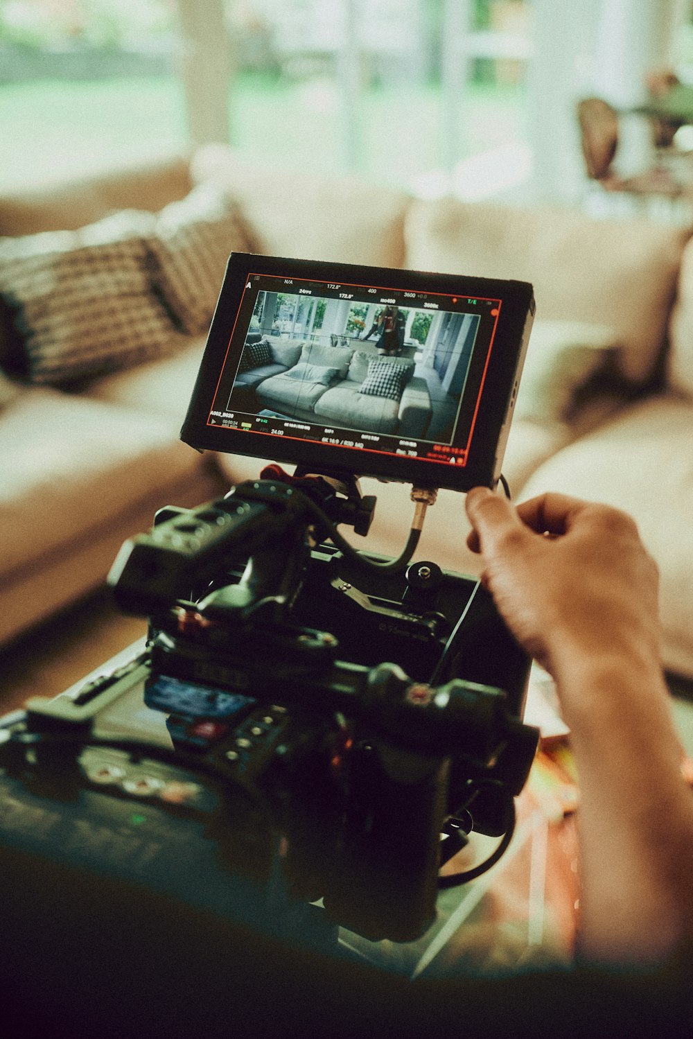 Una persona sosteniendo una cámara de video frente a un sofá