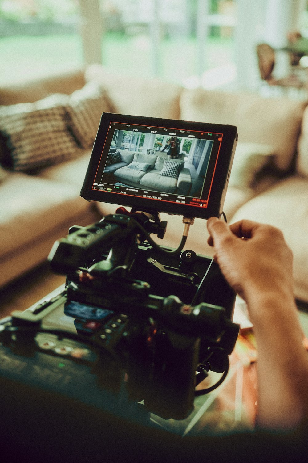 a person holding a video camera in front of a couch