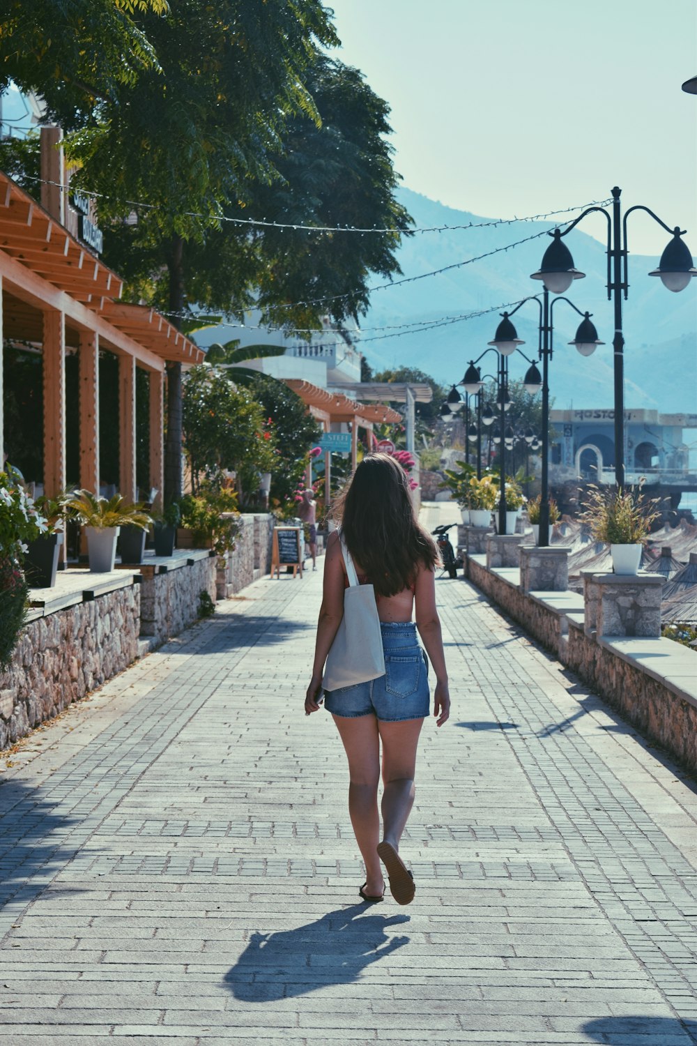 a woman walking down a street next to a light pole