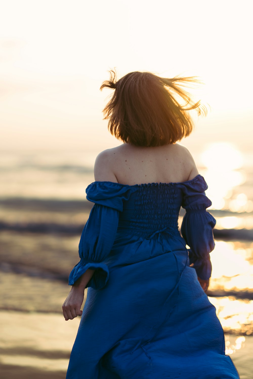 Una donna in un vestito blu che cammina sulla spiaggia