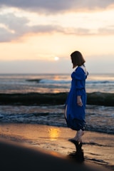 Model wearing high-waisted leggings in ocean blue, walking barefoot on the beach at sunset