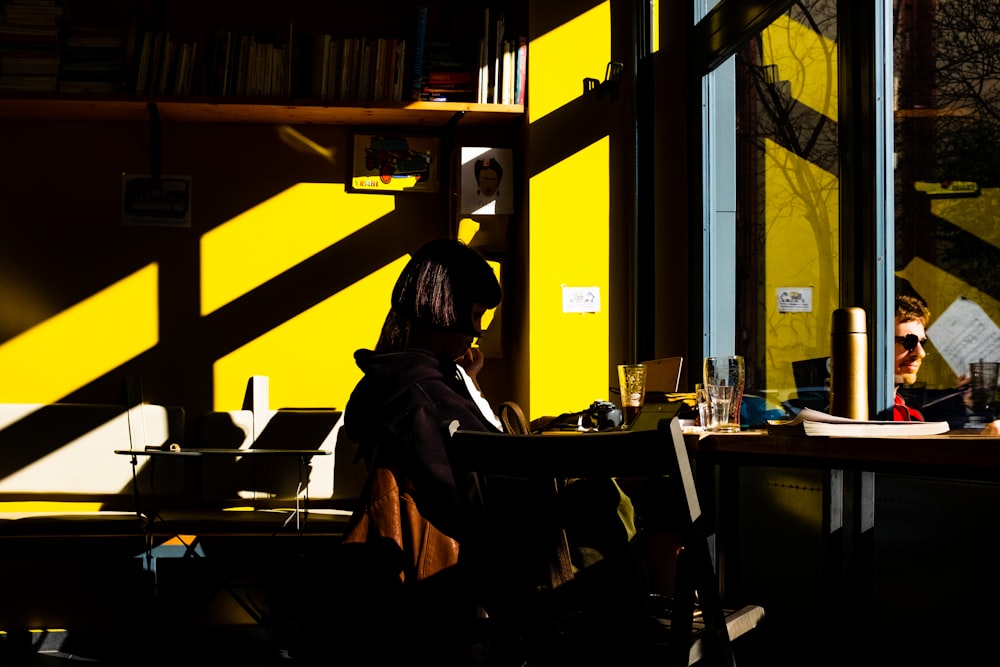 a woman sitting at a table with a laptop computer