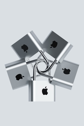 Multiple silver padlocks are interconnected, each displaying a prominent logo in black on the front surface. The locks are arranged in a symmetrical, radial pattern against a pale background.