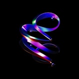 A digital artwork featuring a swirling, ribbon-like structure with a gradient of vibrant colors including blue, purple, green, and red. Reflective spheres are embedded along the structure, all set against a stark black background that enhances the dramatic contrast and luminescence of the design.