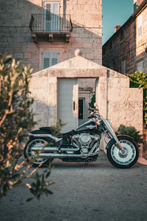 A sleek motorcycle parked beside a rustic Spanish countryside road at sunset, with a cozy restaurant visible in the background.