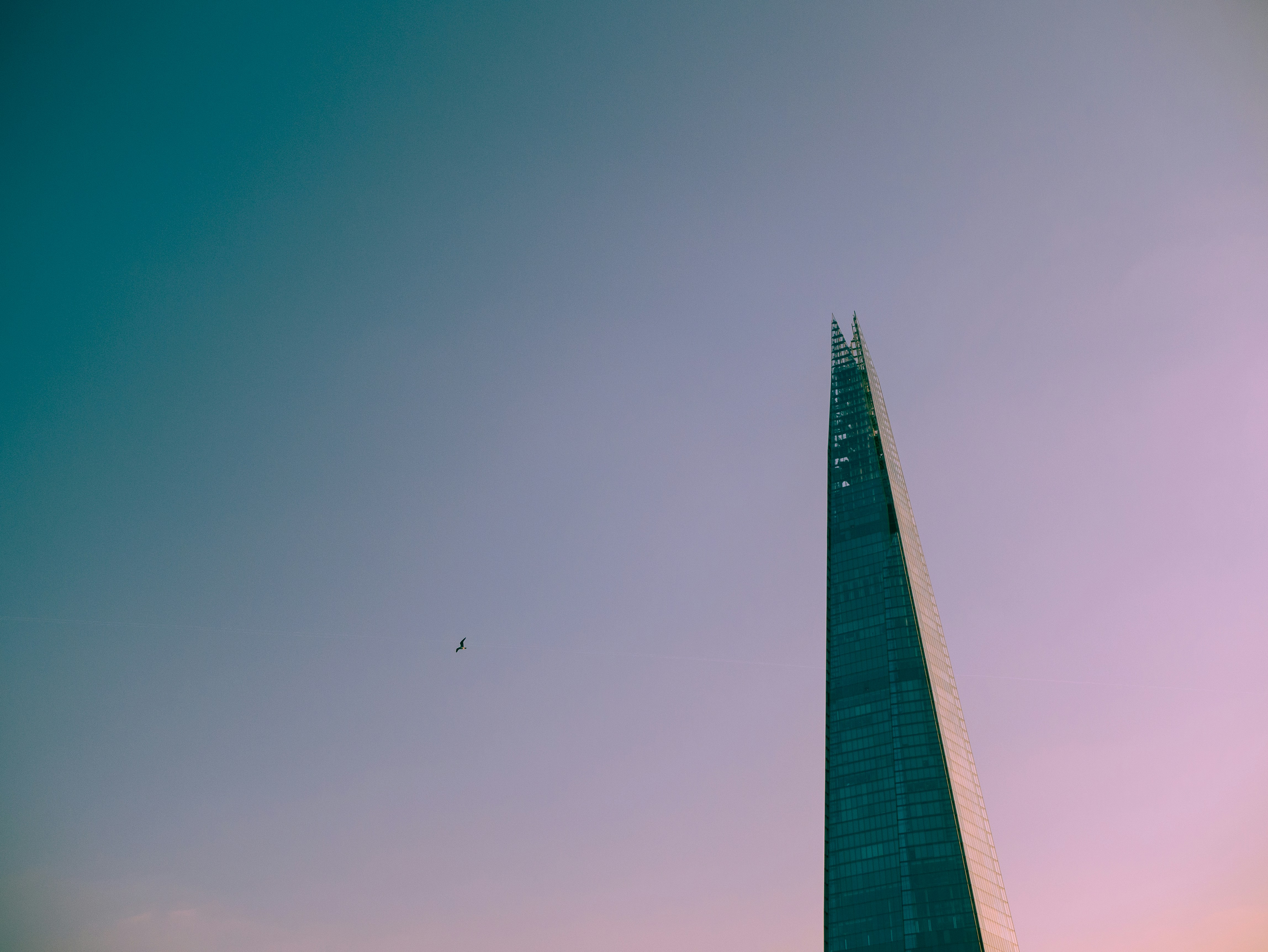 Ein sehr hohes Gebäude mit einem Flugzeug, das am Himmel fliegt