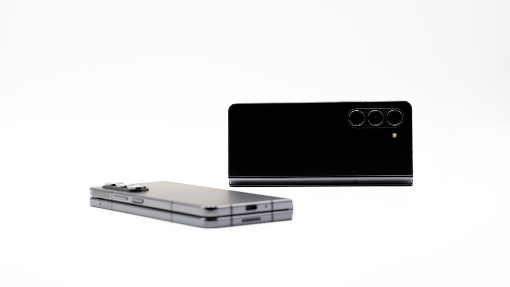 Ein silbernes Handy sitzt neben einem schwarzen Handy
